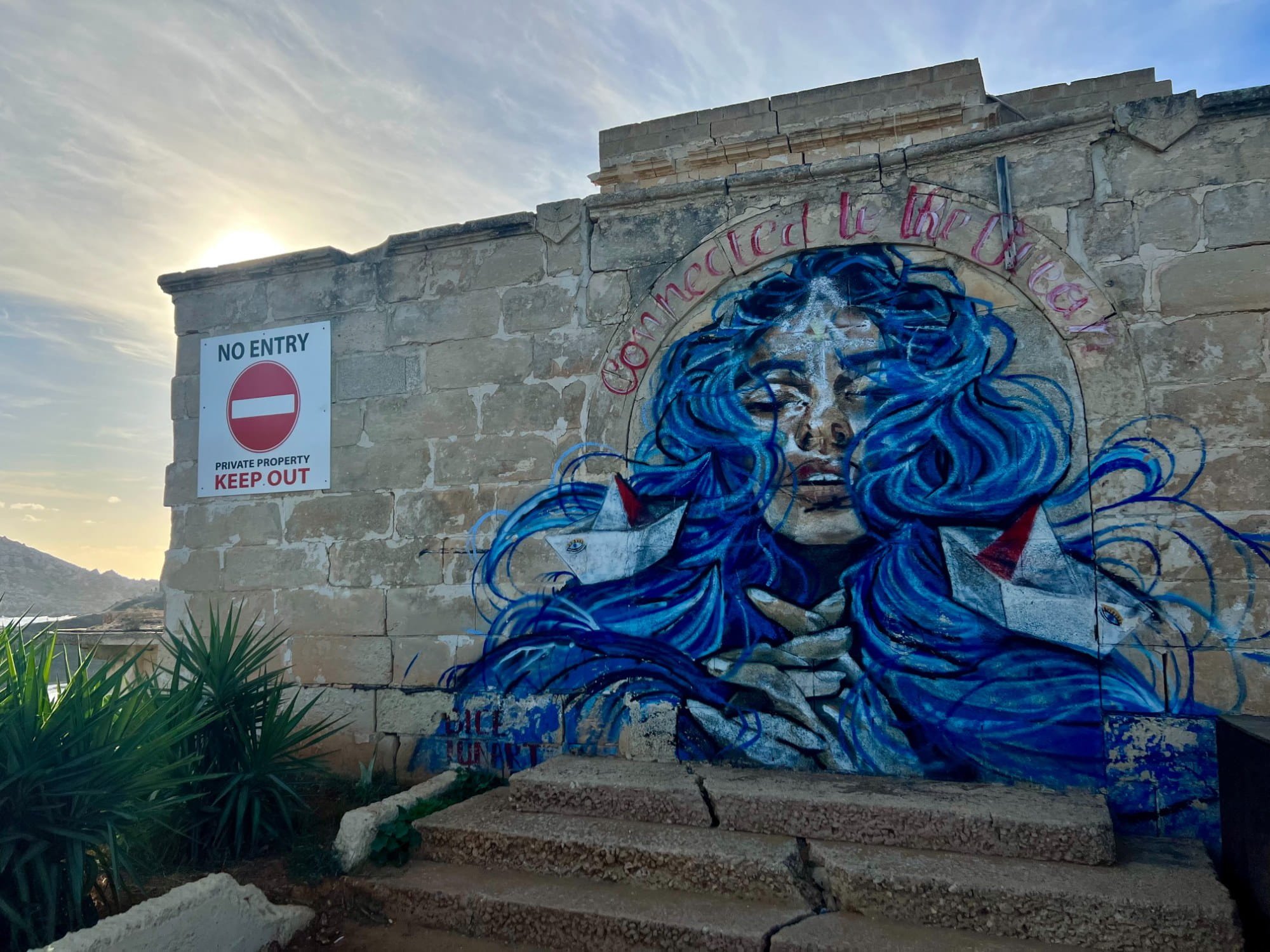 "Connected to the Ocean" mural painted on a wall near the beach entrance.