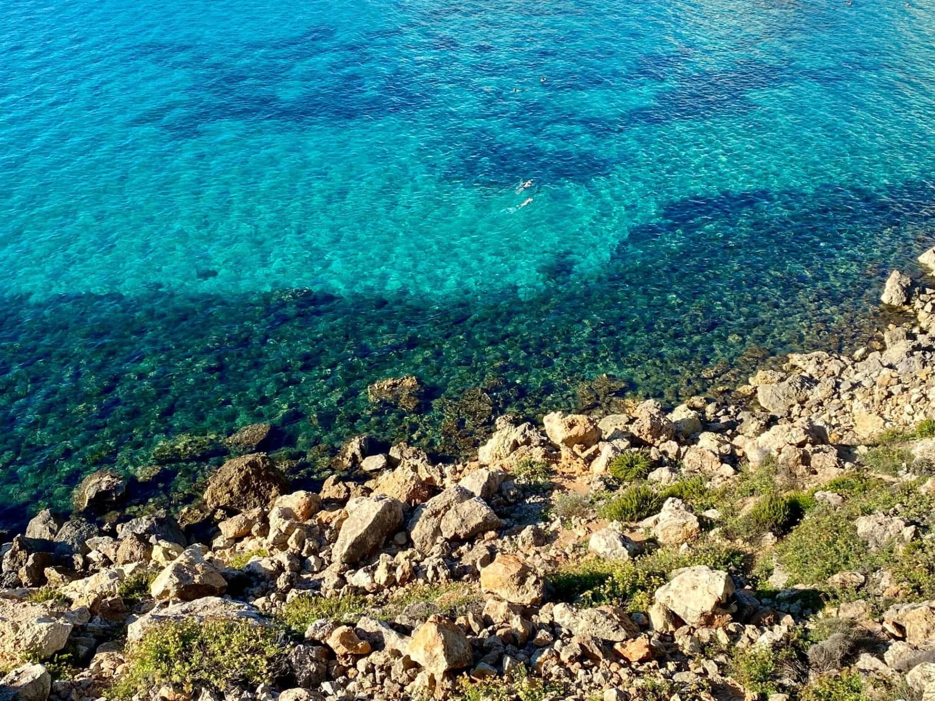 Crystal clear turquoise sea water over a rocky seabed, perfect for snorkeling at Golden Bay.