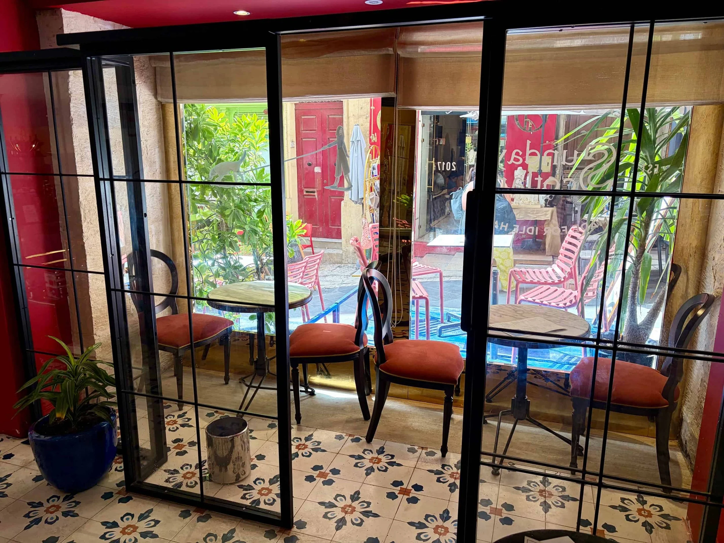 Cozy indoor seating viewed through a black-framed glass wall at Sunday in Scotland, Valletta.