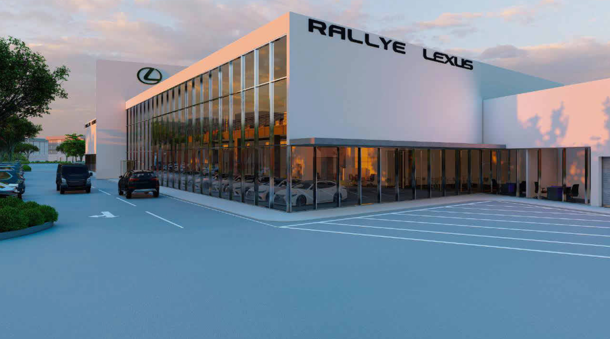 Modern automotive dealership building with Lexus and Rallye signage, glass facade, parking lot with several cars, trees, and a partly cloudy sky at sunset.