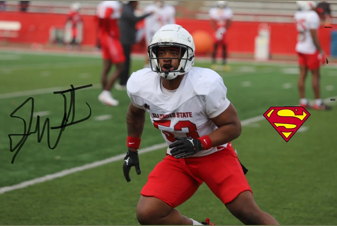 Football player in white and red uniform on a football field, with a Superman logo worn on the uniform, and an autograph on the bottom left corner.
