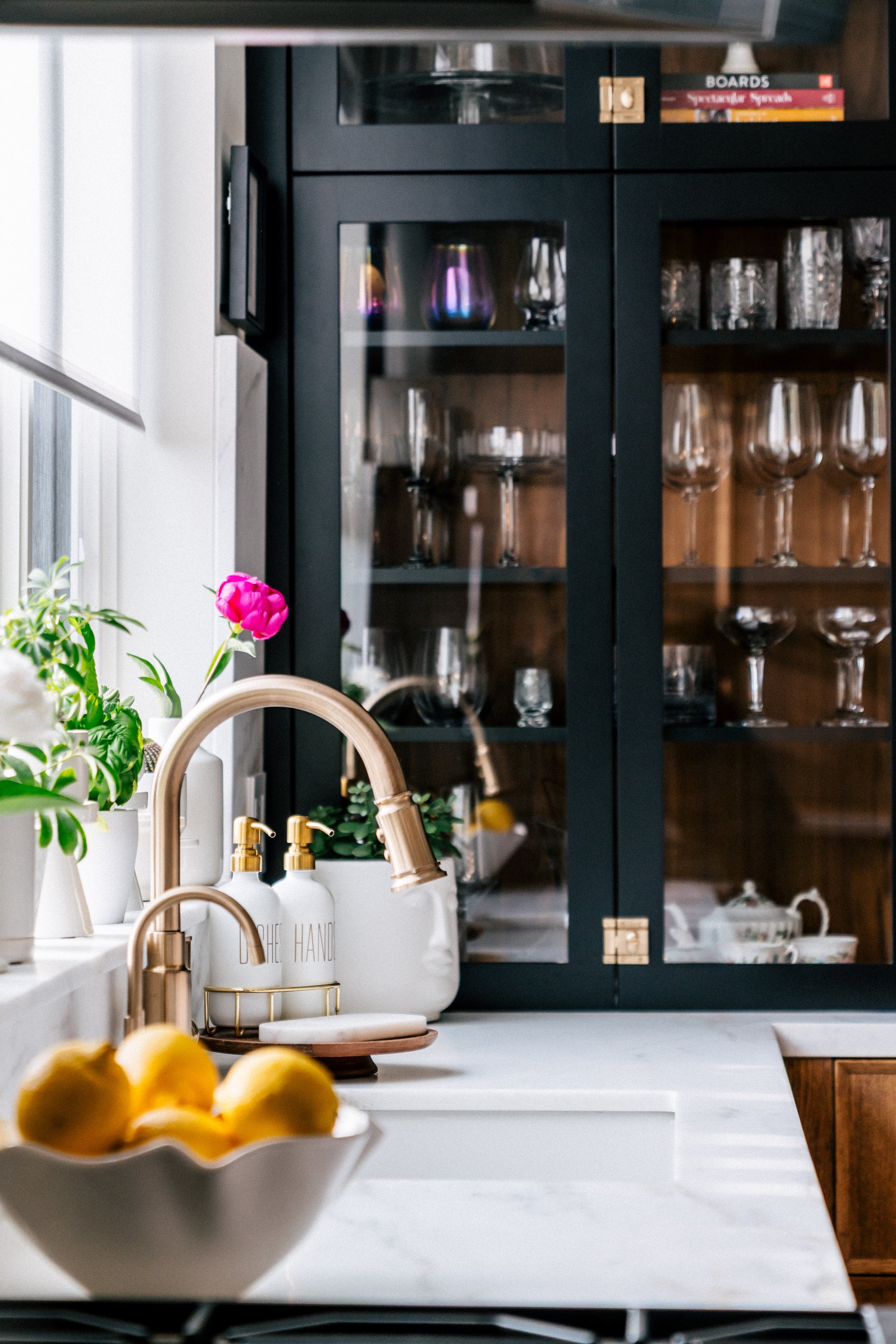 interior design of a kitchen with marble countertops, black upper glass cabinets and walnut wood lower cabinets.