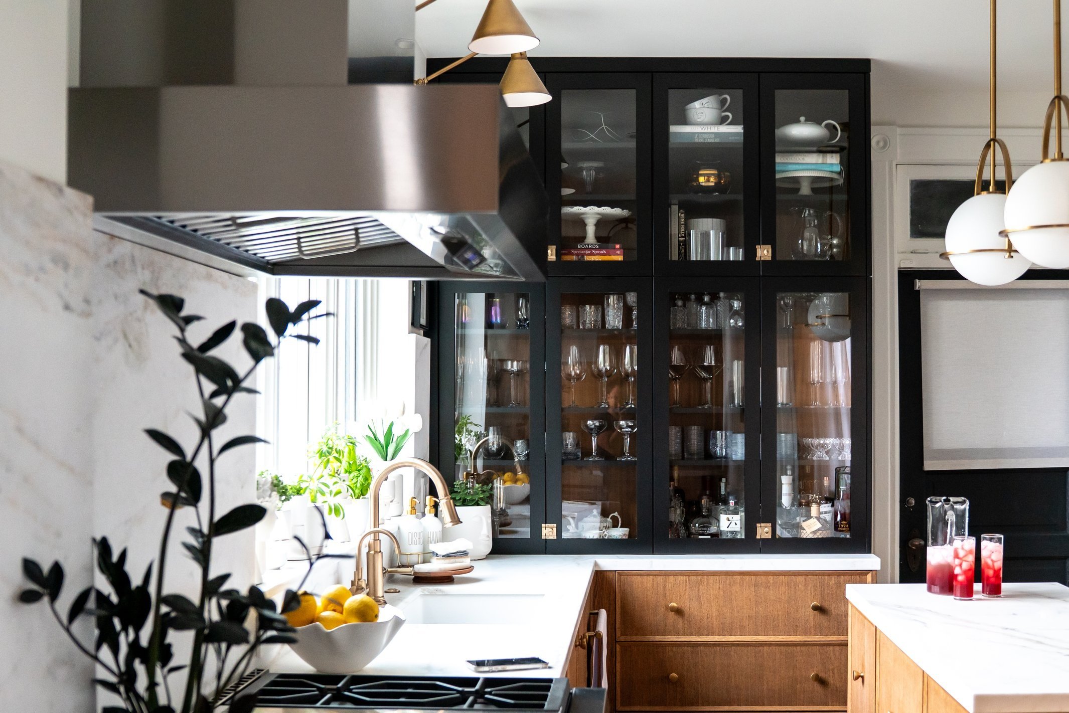 interior design of a kitchen with dark wood glass upper cabinets with a walnut lower cabinet with marble countertops