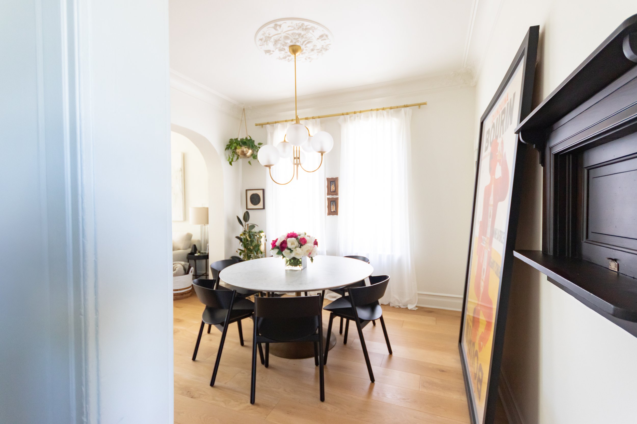 interior design of a traditional dining room, light wood floors, grand chandelier, marble dining table and a large piece of art against the wall.