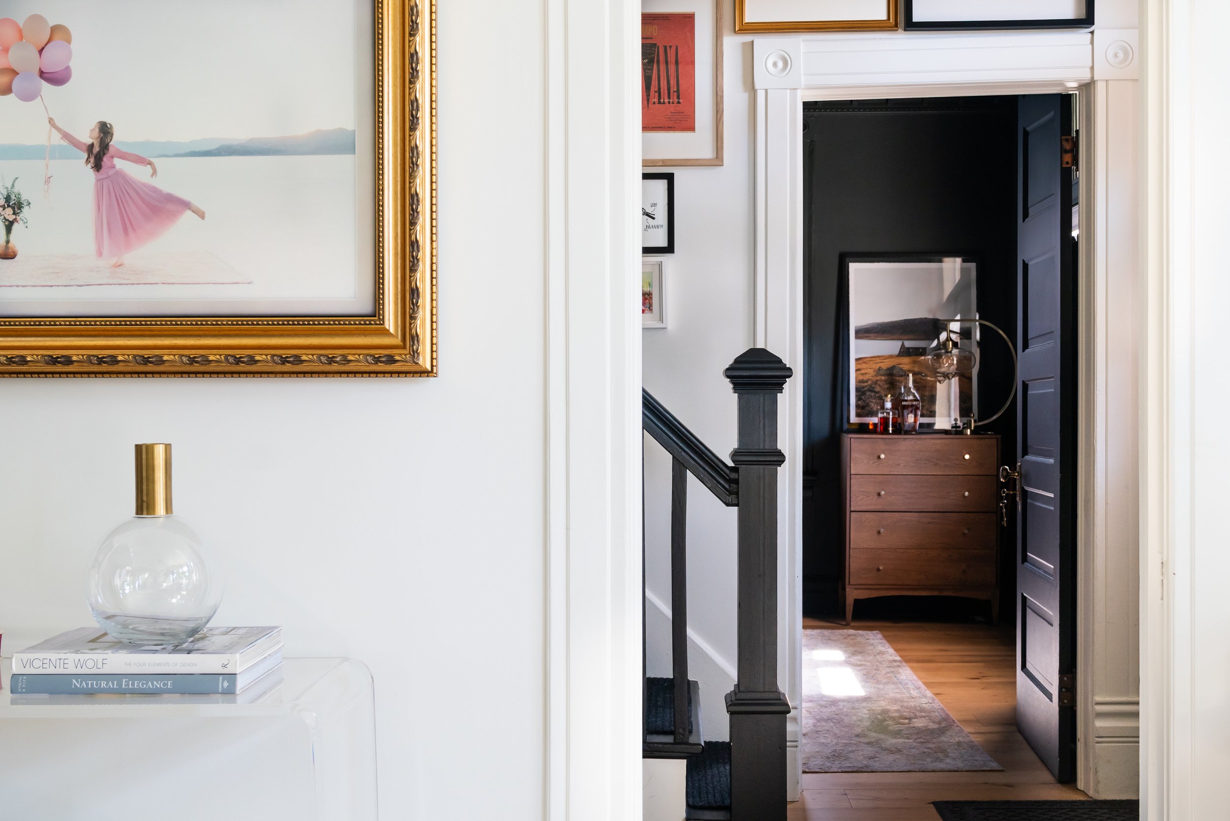 interior design of a moody dark office against a white hallway full of artwork