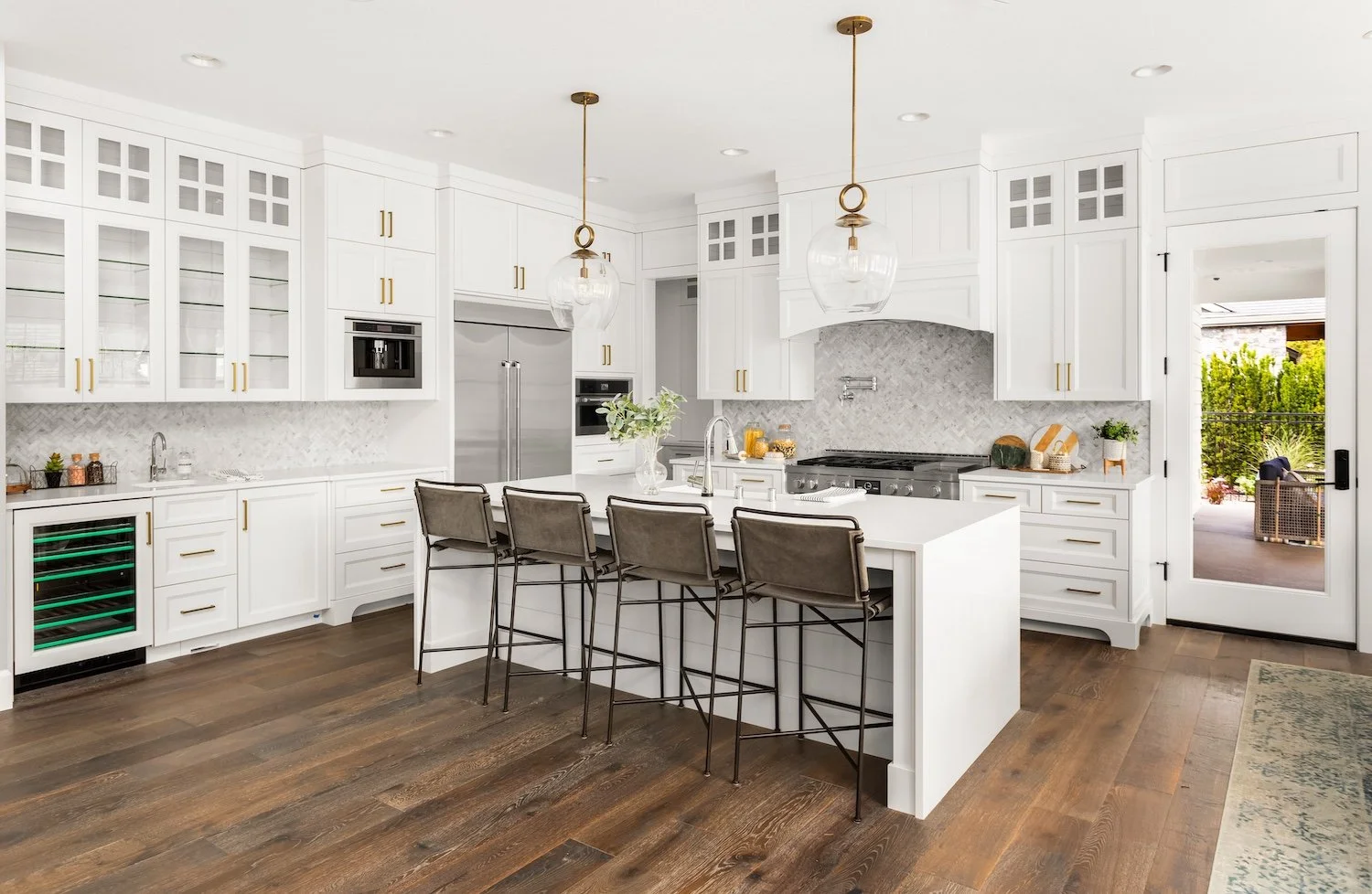 Beautiful white kitchen with high quality cabinetry, with waterfall island, stainless steel appliances, and hardwood floors.