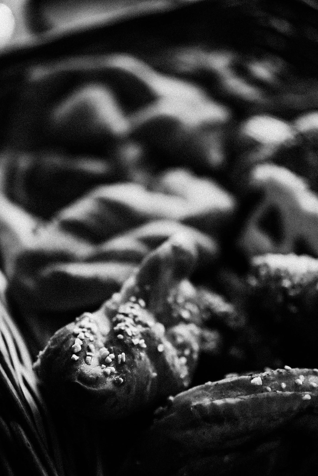 Close-up of candies in a basket, including a snake-shaped treat with salt on top and twisted striped candies in the background, all in black and white.