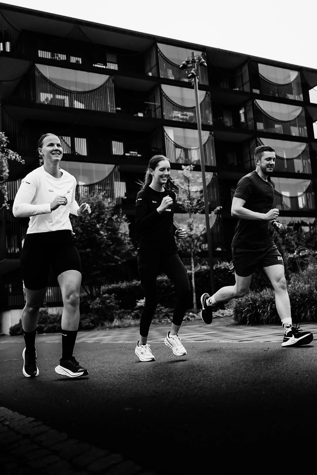 Three people jogging together outdoors near a modern residential building.