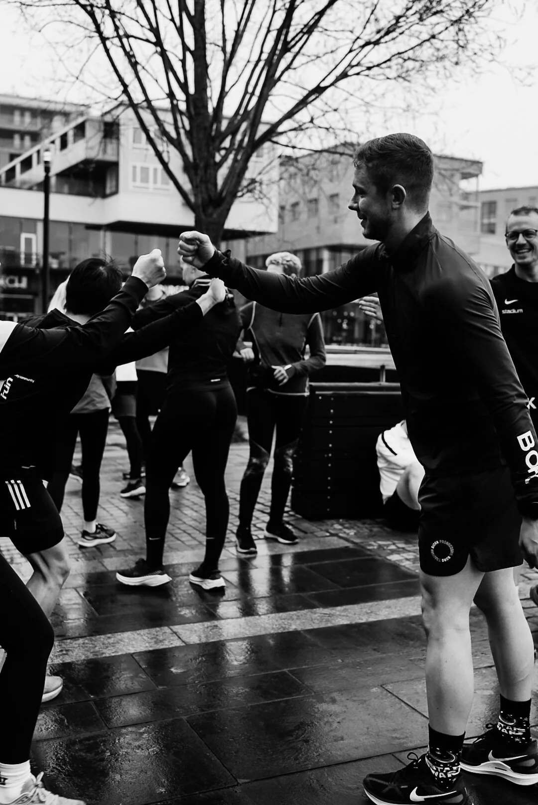 People in athletic clothing giving fist bumps outdoors during rainy weather.