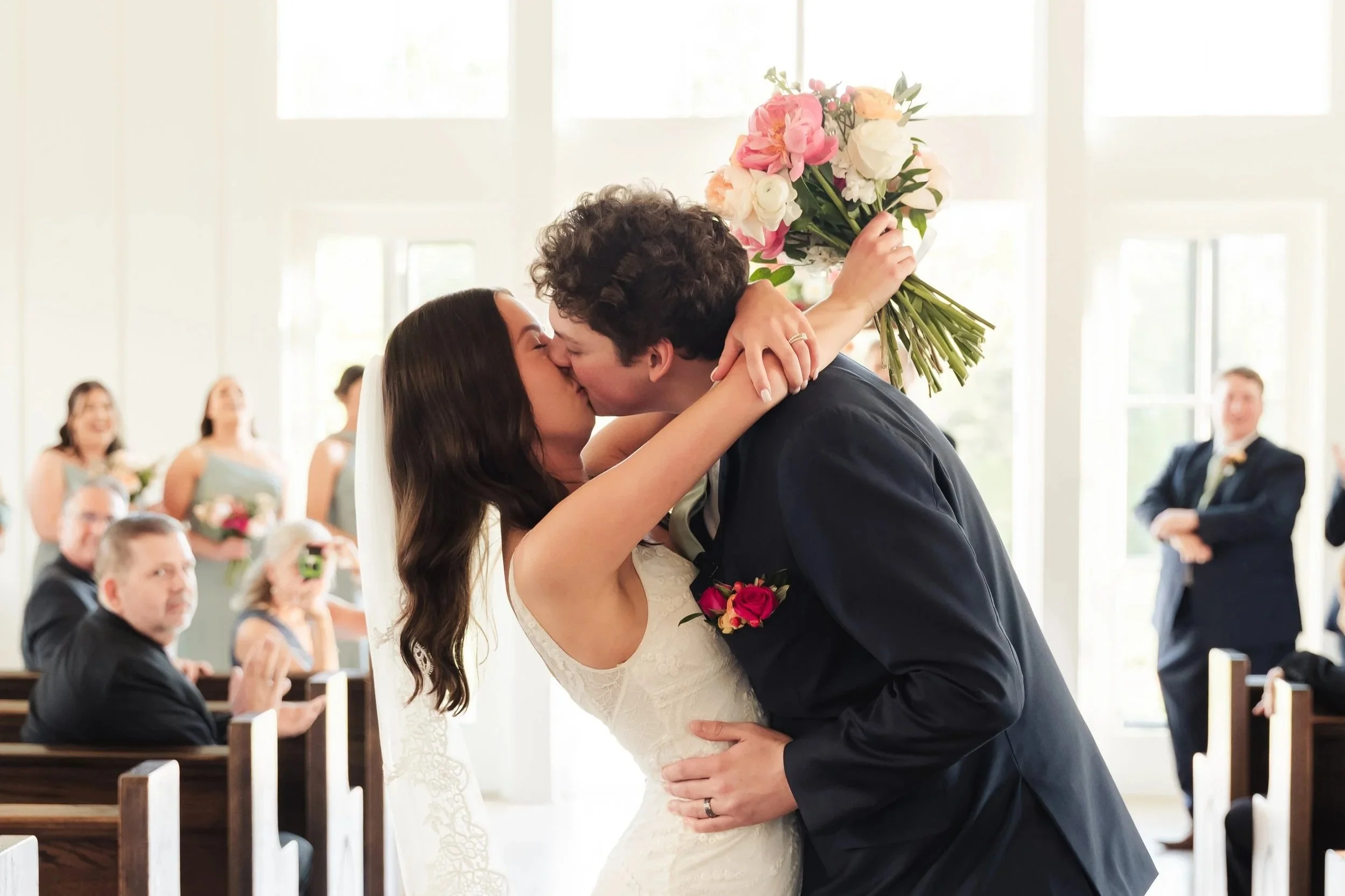 Couple kissing at the end of aisle of wedding with church pews in the background in Nashville Tennessee at The Birchwood venue.