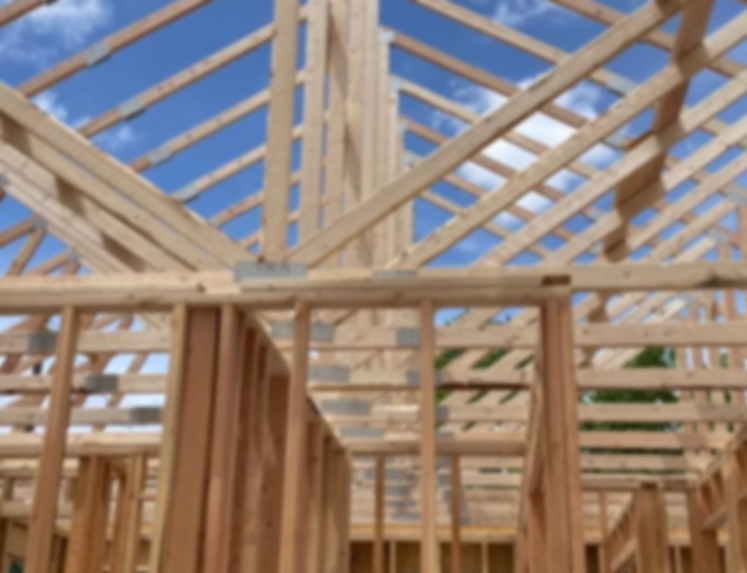 Wooden framework of a house under construction against a blue sky.