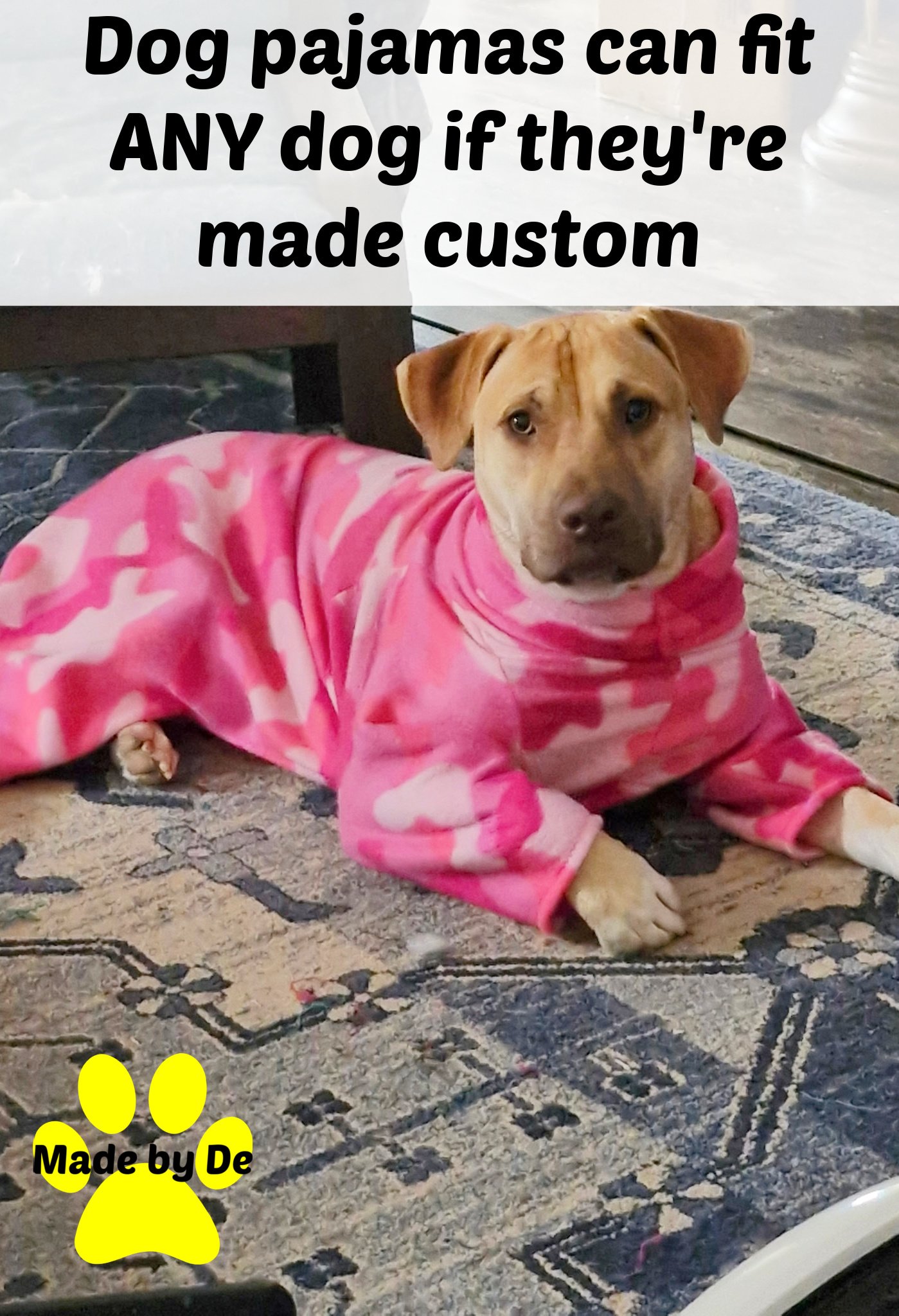 Tan dog wearing pink camo pajamas lying on the floor