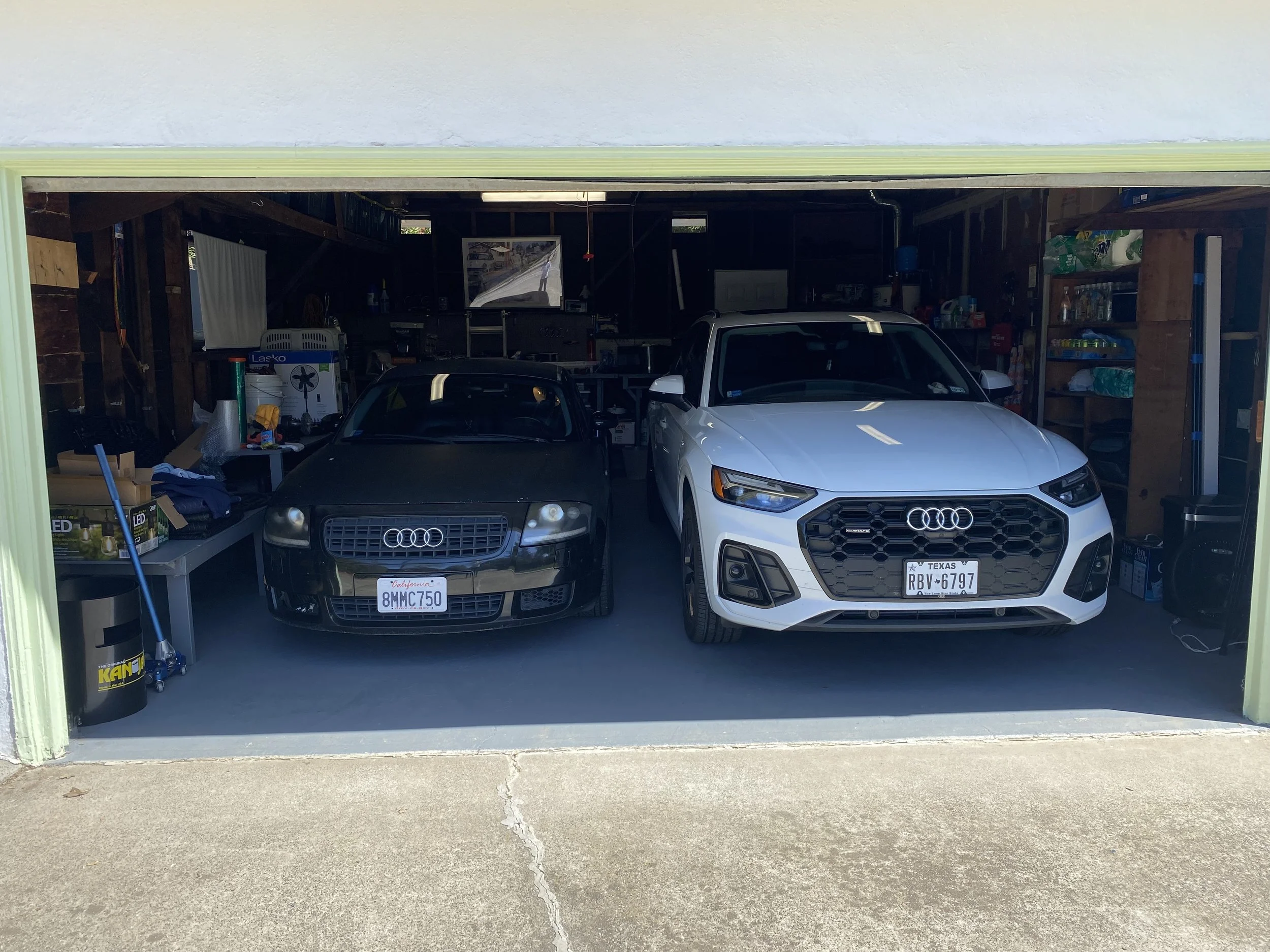 Audi TT and Audi Q5 cars parked inside a garage, with tools and supplies stored on the sides.