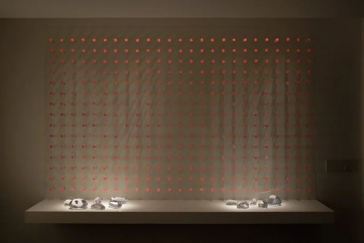 luz ou cor?
De início parecem apenas objetos pintados de uma cor opaca, espécie de batons arranjados sobre um painel vertical.
Nem parece que aquelas cores, um vermelho terroso, um azul cinzento, são, na verdade, luz. Apenas quando o ambiente se