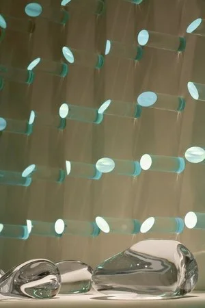 luz ou cor?
De início parecem apenas objetos pintados de uma cor opaca, espécie de batons arranjados sobre um painel vertical.
Nem parece que aquelas cores, um vermelho terroso, um azul cinzento, são, na verdade, luz. Apenas quando o ambiente se