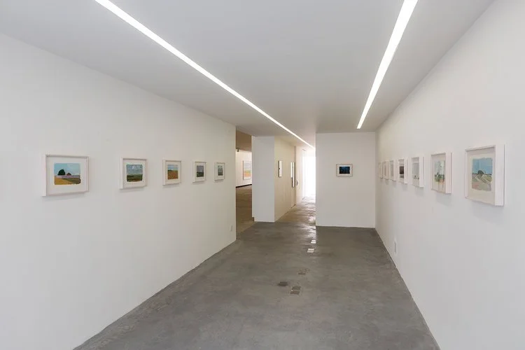 A recepção, originalmente pensada como um espaço não-expositivo, ganhou linhas de luz contínuas junto às paredes - que terminaram por atender convenientemente também a função expositiva.