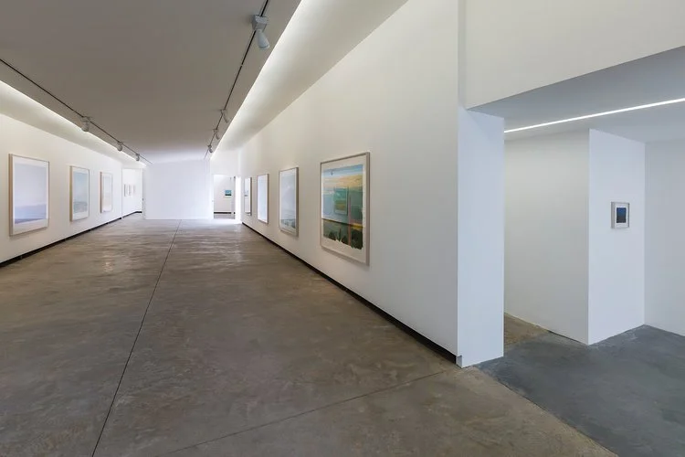 Uma lâmina de gesso, destacada do teto e acompanhando a inclinação da cobertura original, abriga a iluminação difusa-assimétrica para as paredes, complementada por projetores em trilhos para destaque das obras.