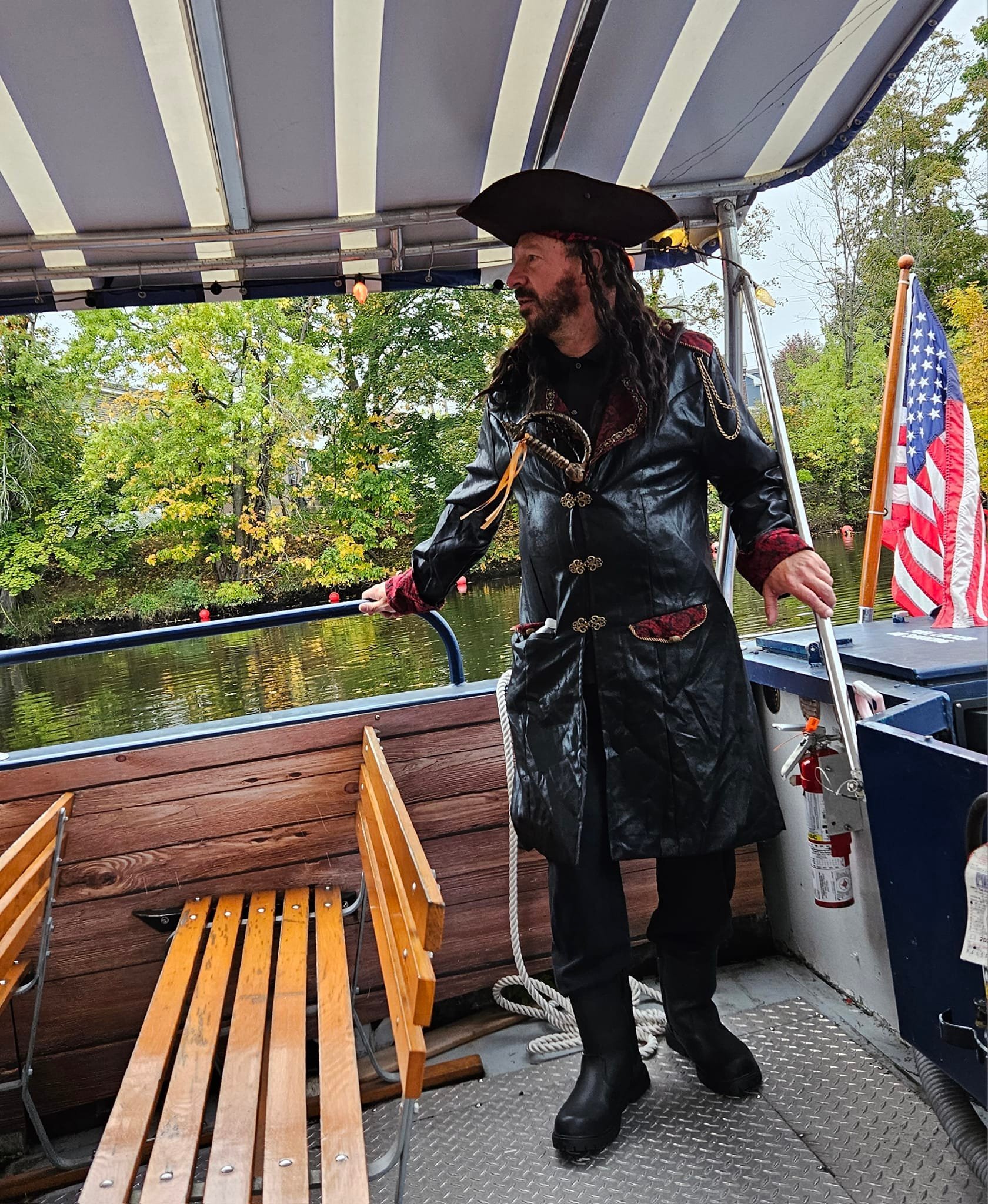 A person dressed as a pirate on a boat with an American flag in the background.