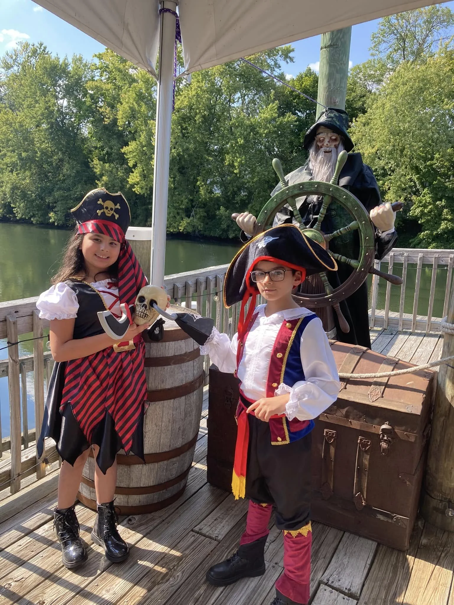 Children dressed as pirates on a pirate ship with a skeleton figure at the helm.
