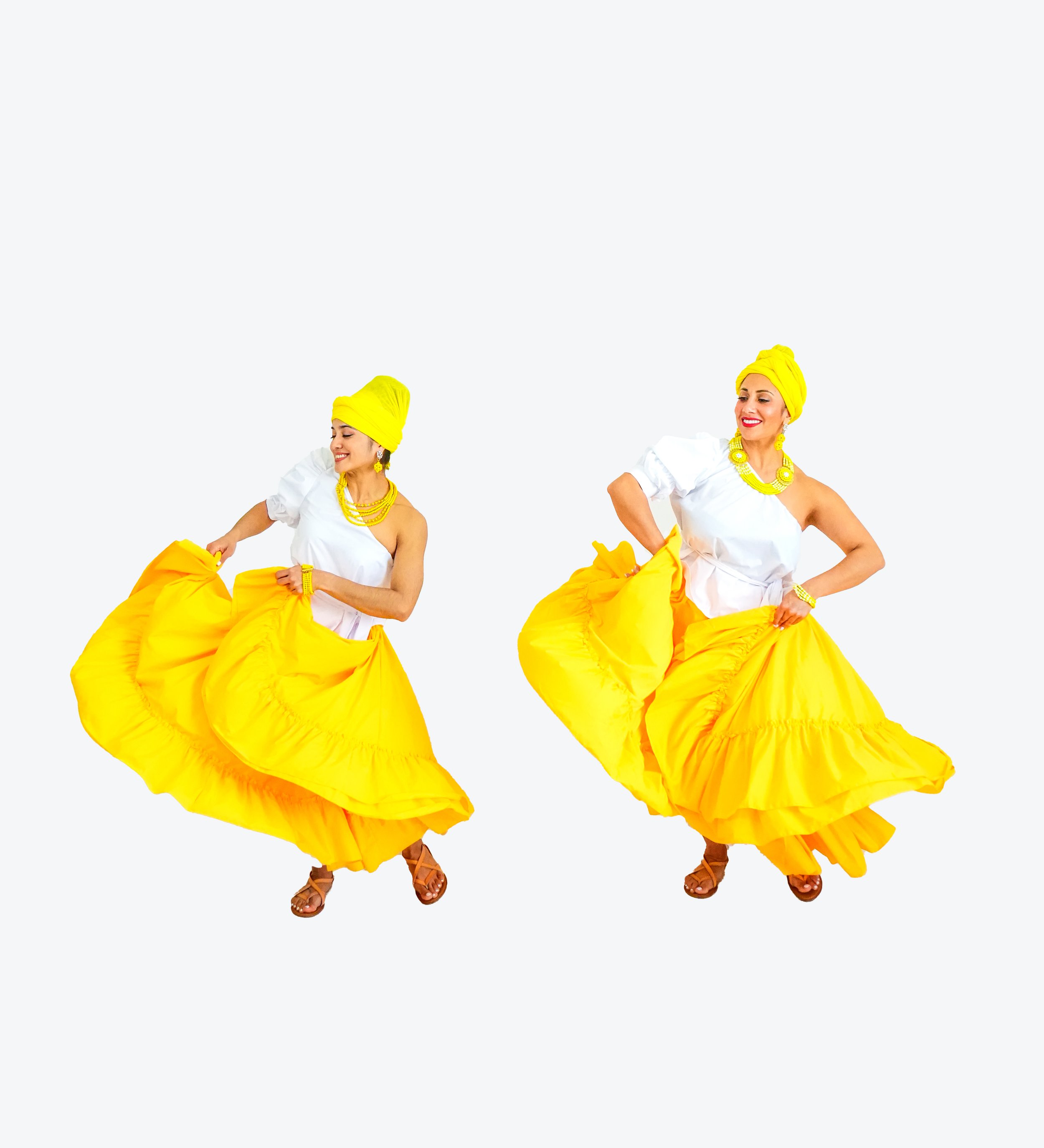Two women dressed in white tops and bright yellow skirts, yellow headwraps, and yellow jewelry, dancing happily against a white background.