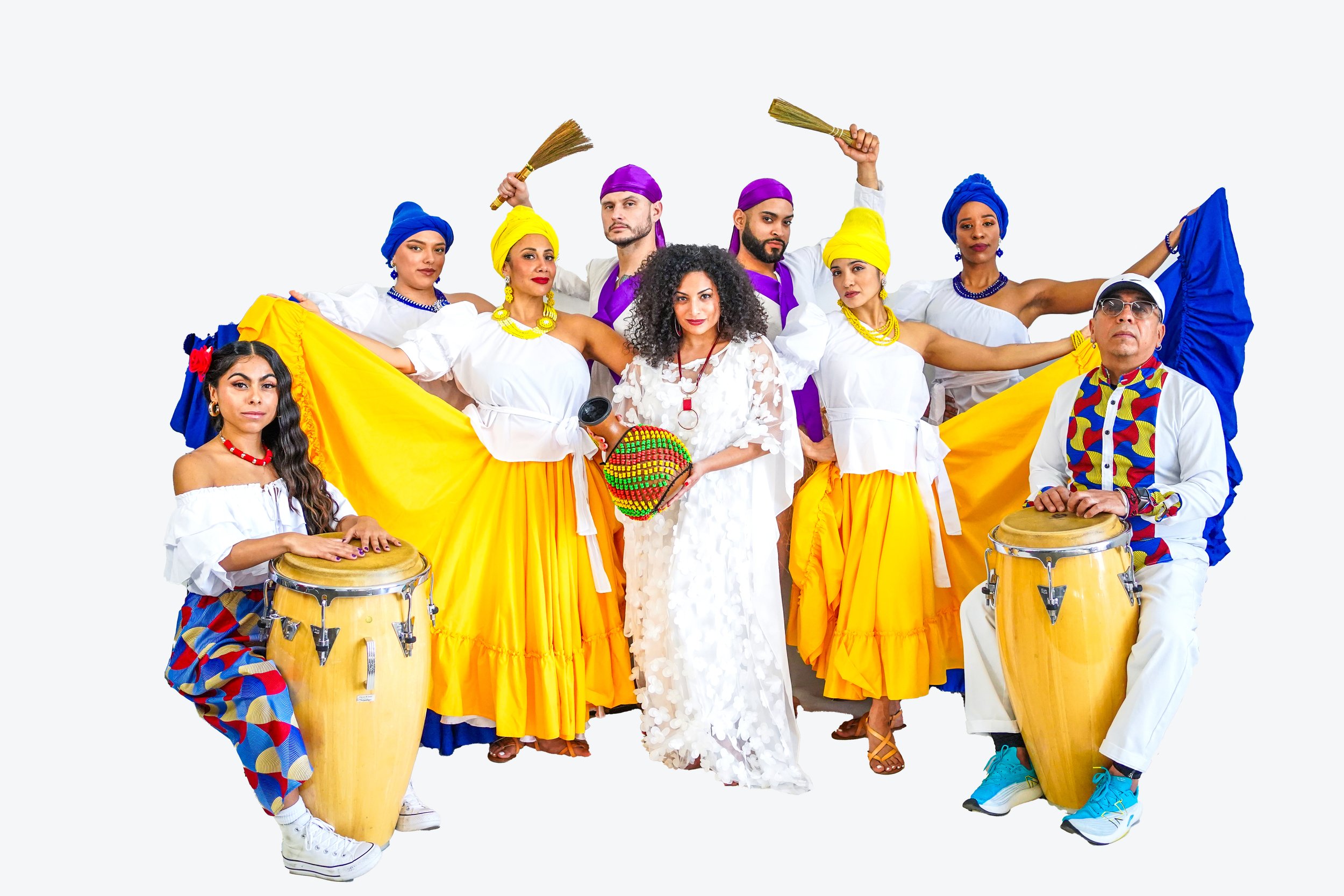 Group of people dressed in traditional Colombian attire, holding musical instruments, with some in yellow skirts, white tops, and colorful headscarves, performing and posing together.