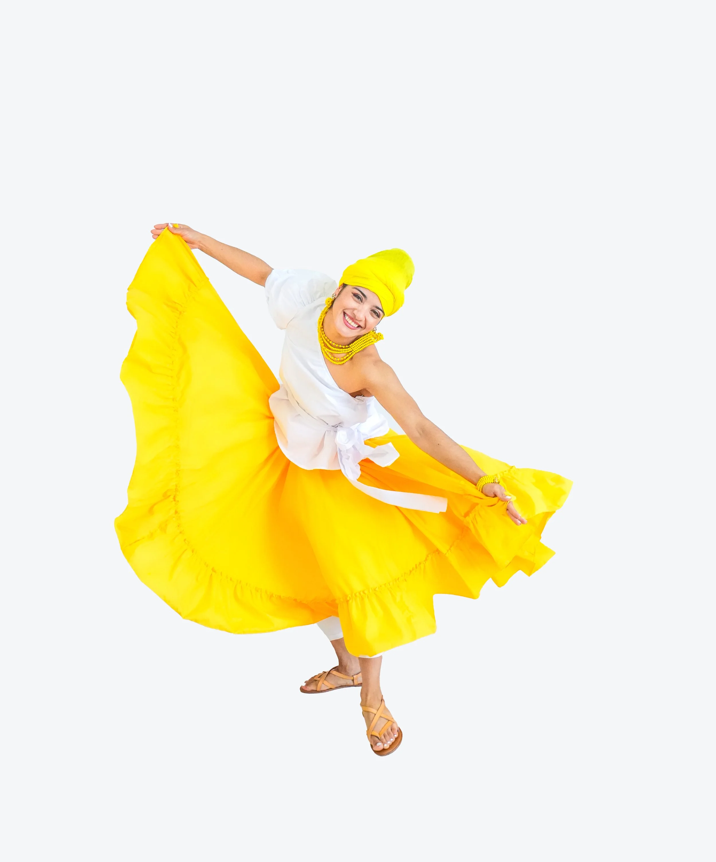 Woman in traditional attire dancing with a bright yellow skirt and head wrap, smiling and holding the skirt out as she twirls.