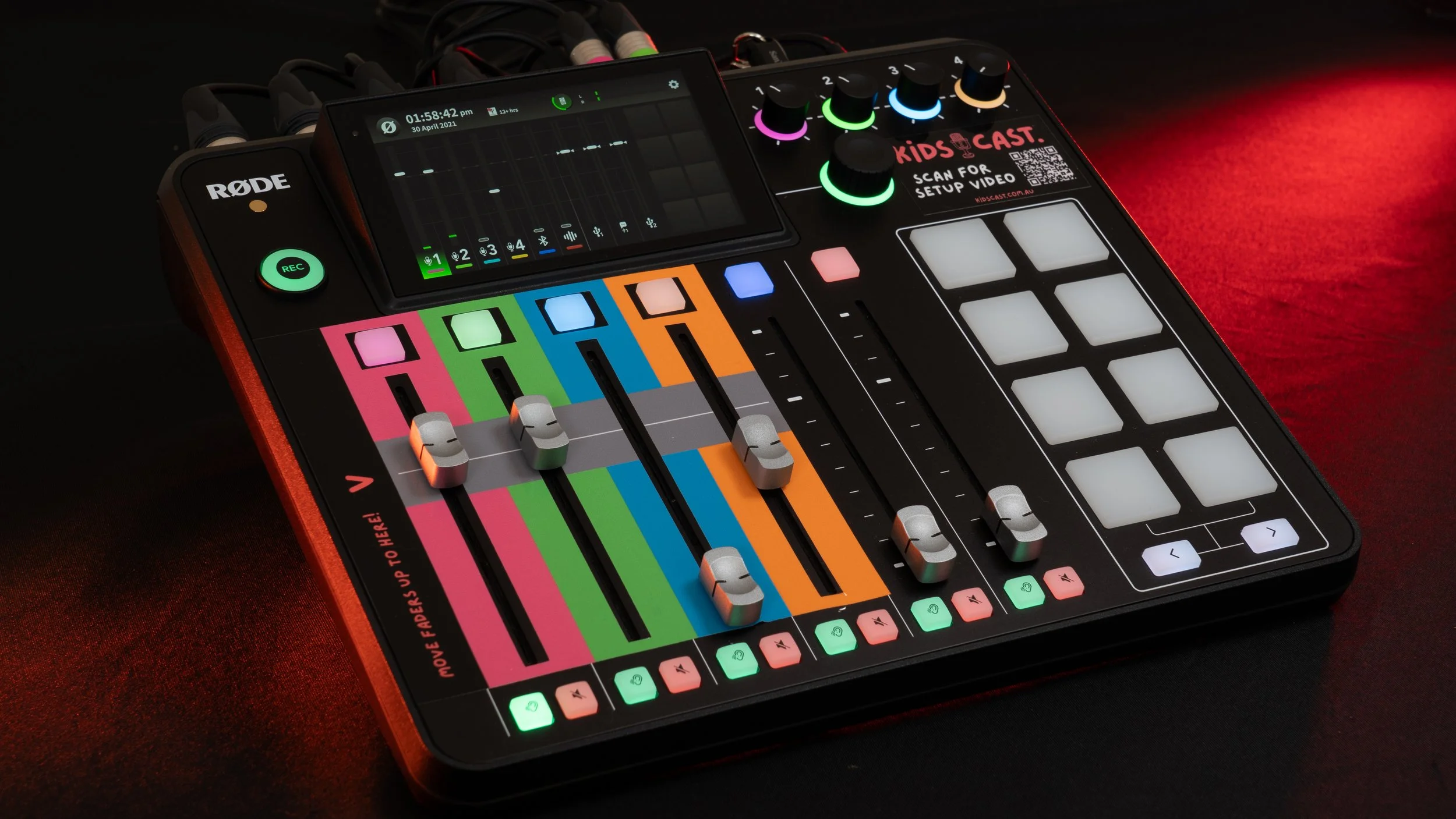 A person using a digital DJ controller with colorful buttons and faders, with a smartphone displaying audio levels and equalizer.