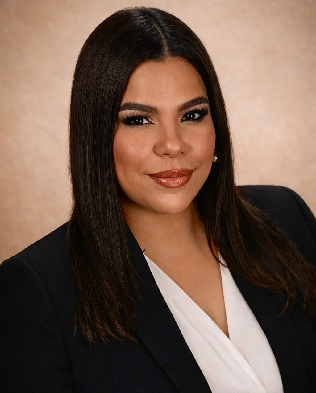 A woman with long black hair, smiling, wearing a black top, against a gray gradient background.