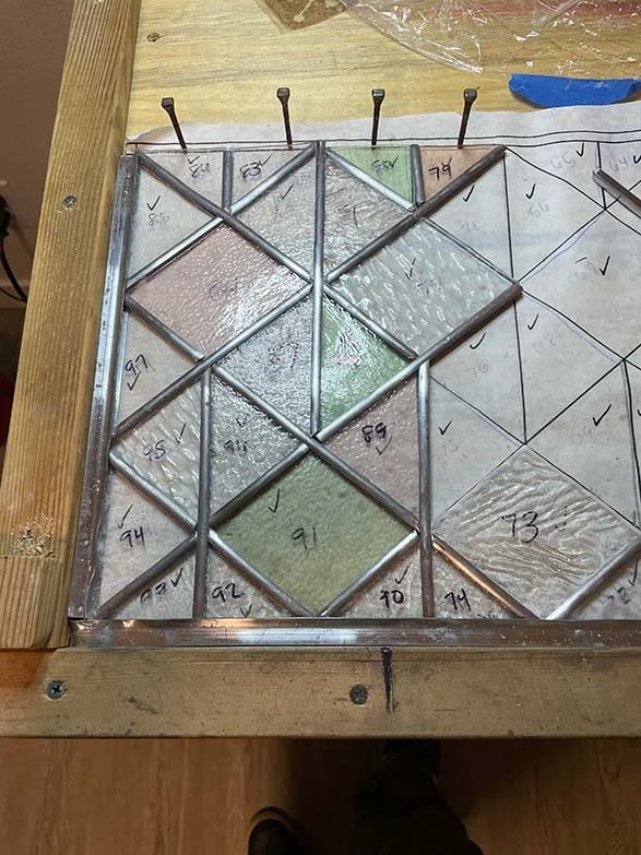 workbench with pastel and clear stained glass windowbeing constructed with lead came