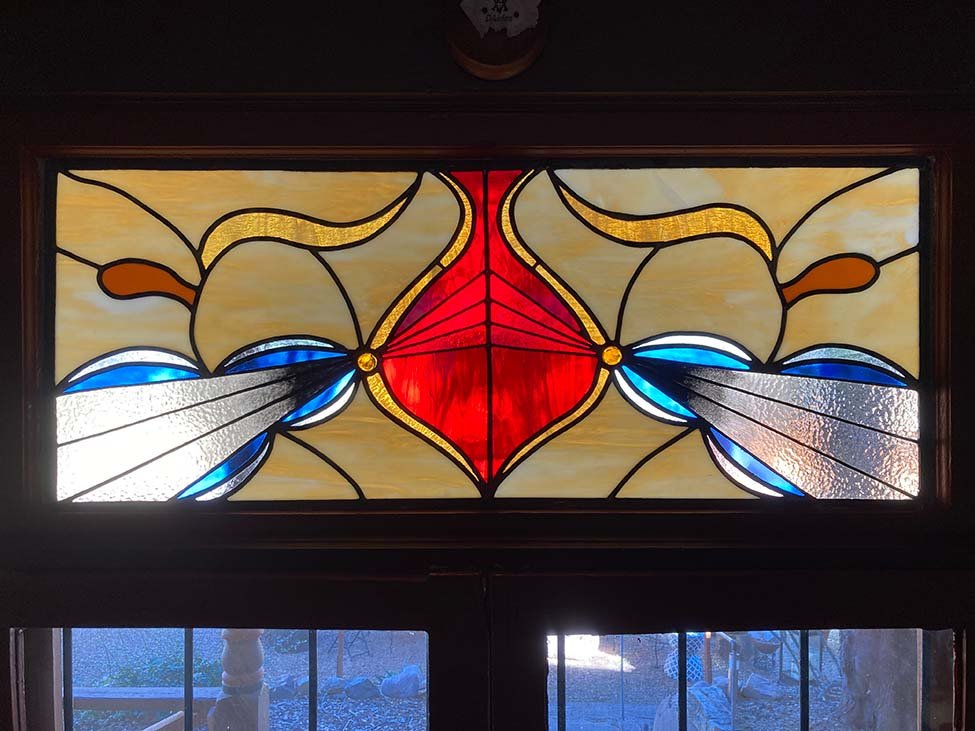 Stained glass window featuring an Amsterdam School design with beige, red, blue, black, and gold colors.