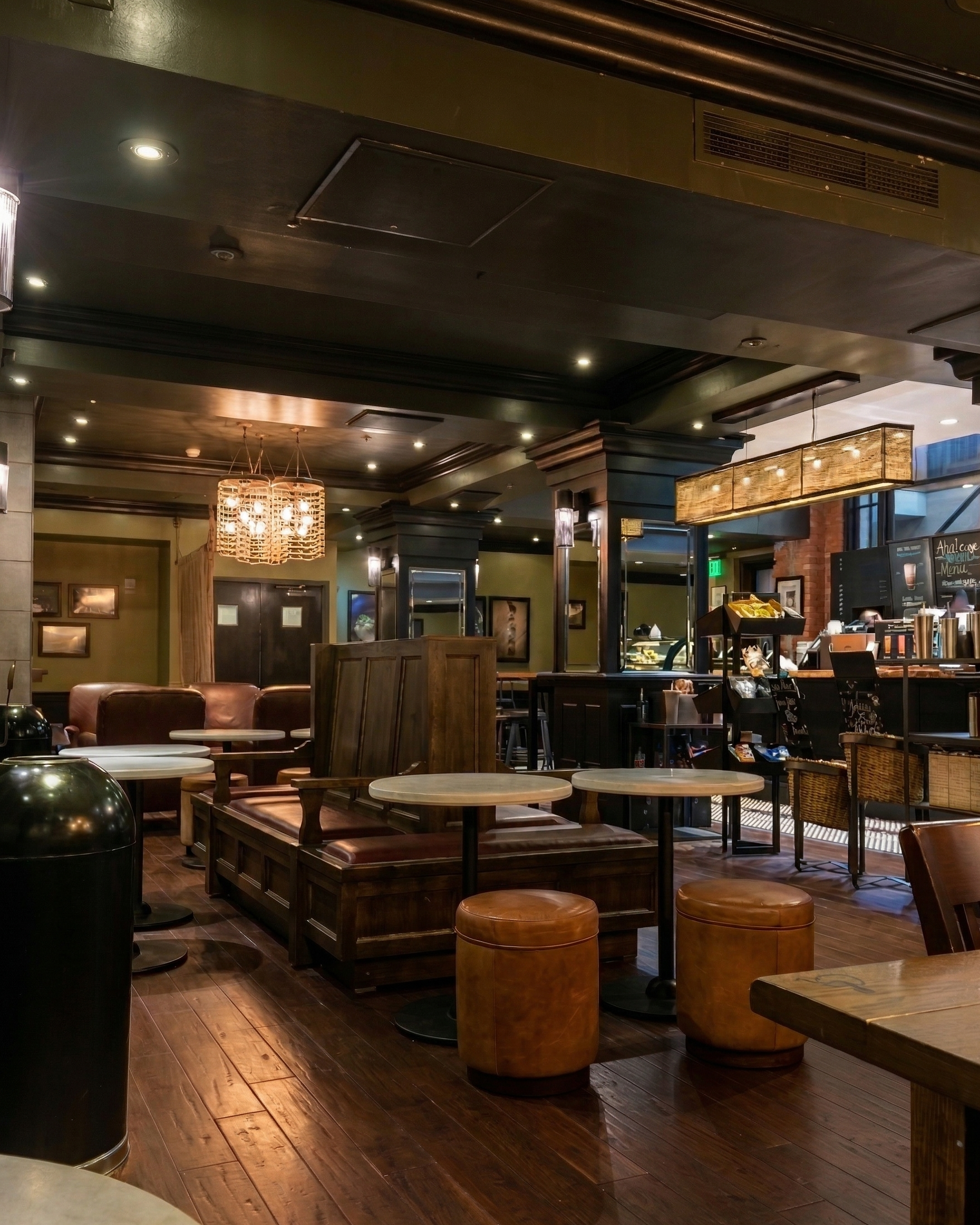 Interior of a cozy coffee shop with wooden furniture, leather chairs, small round tables, and warm lighting.