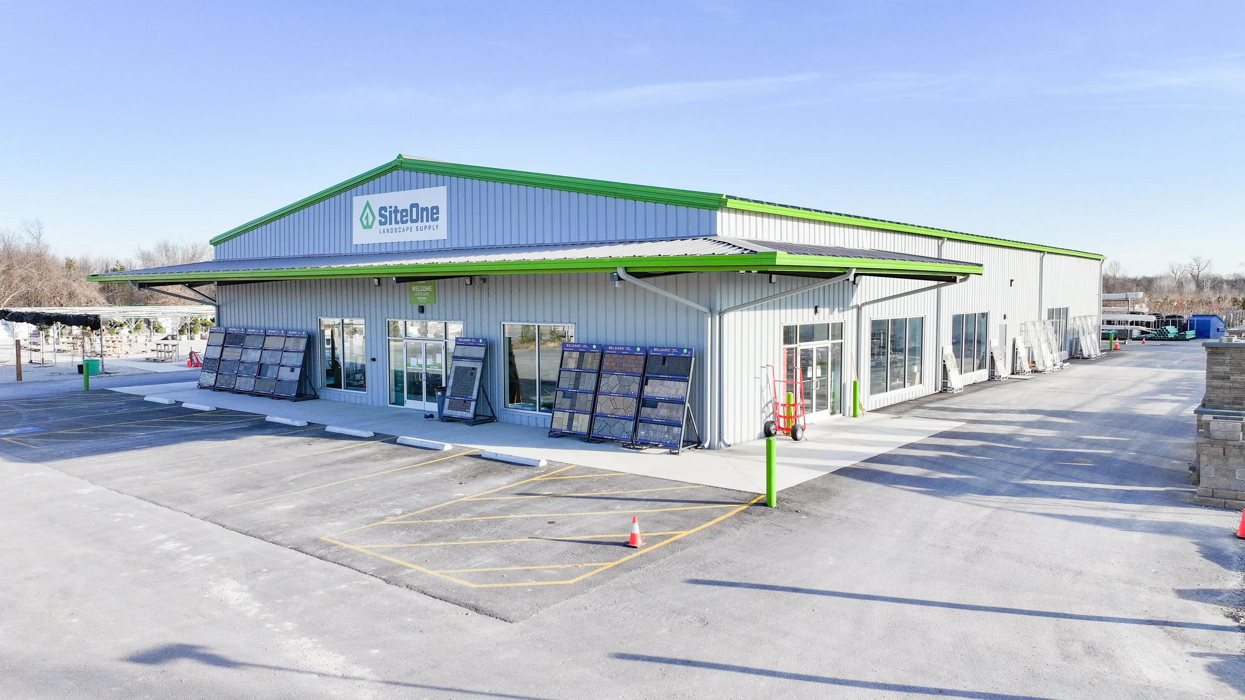 Exterior view of a paint or tile store with display samples outside and a parking lot in front, under a blue sky.