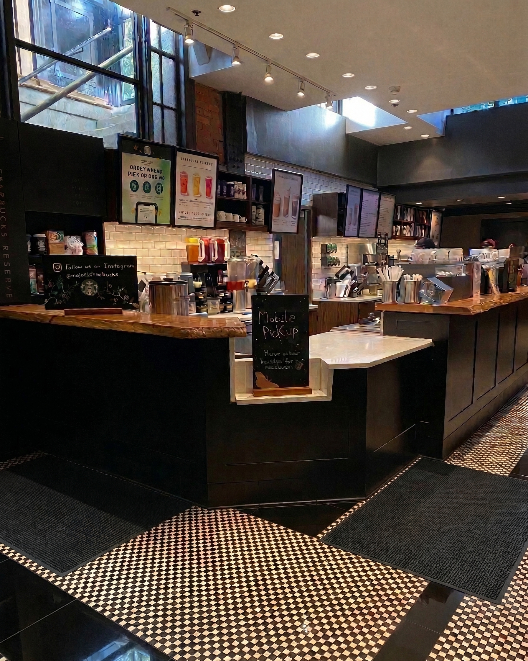 Inside a Starbucks coffee shop, showing the counter with menu screens, coffee machines, and staff preparing drinks.