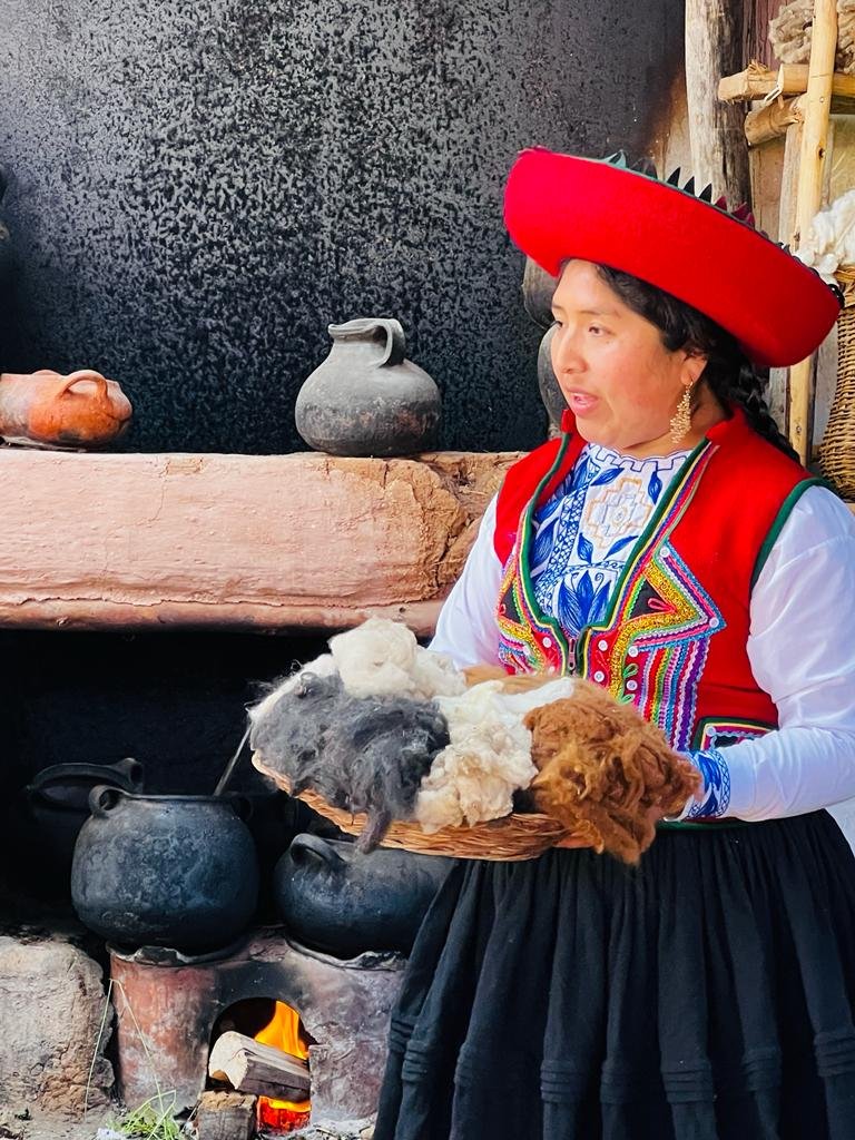 Woman wearing a traditional hat and colorful shawl holding feathers outdoors