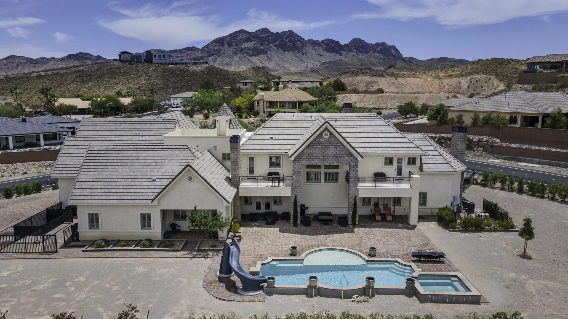 Aerial view of a luxury house with a backyard pool and mountain backdrop.