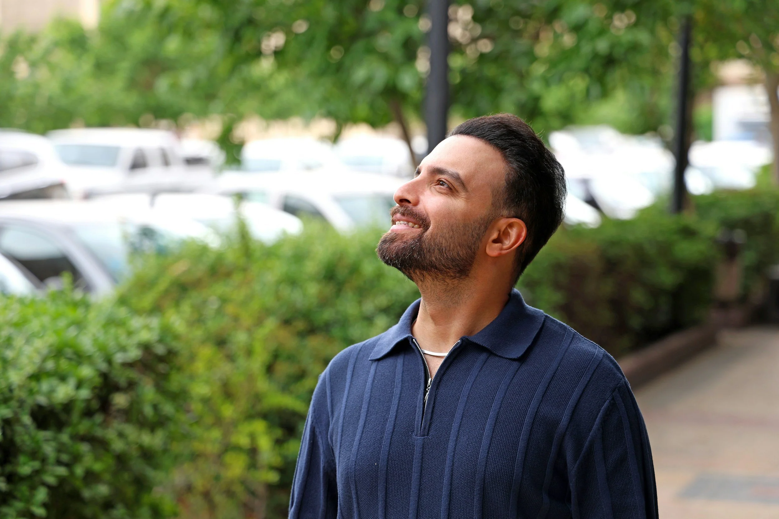 A man outdoors looking up smiling