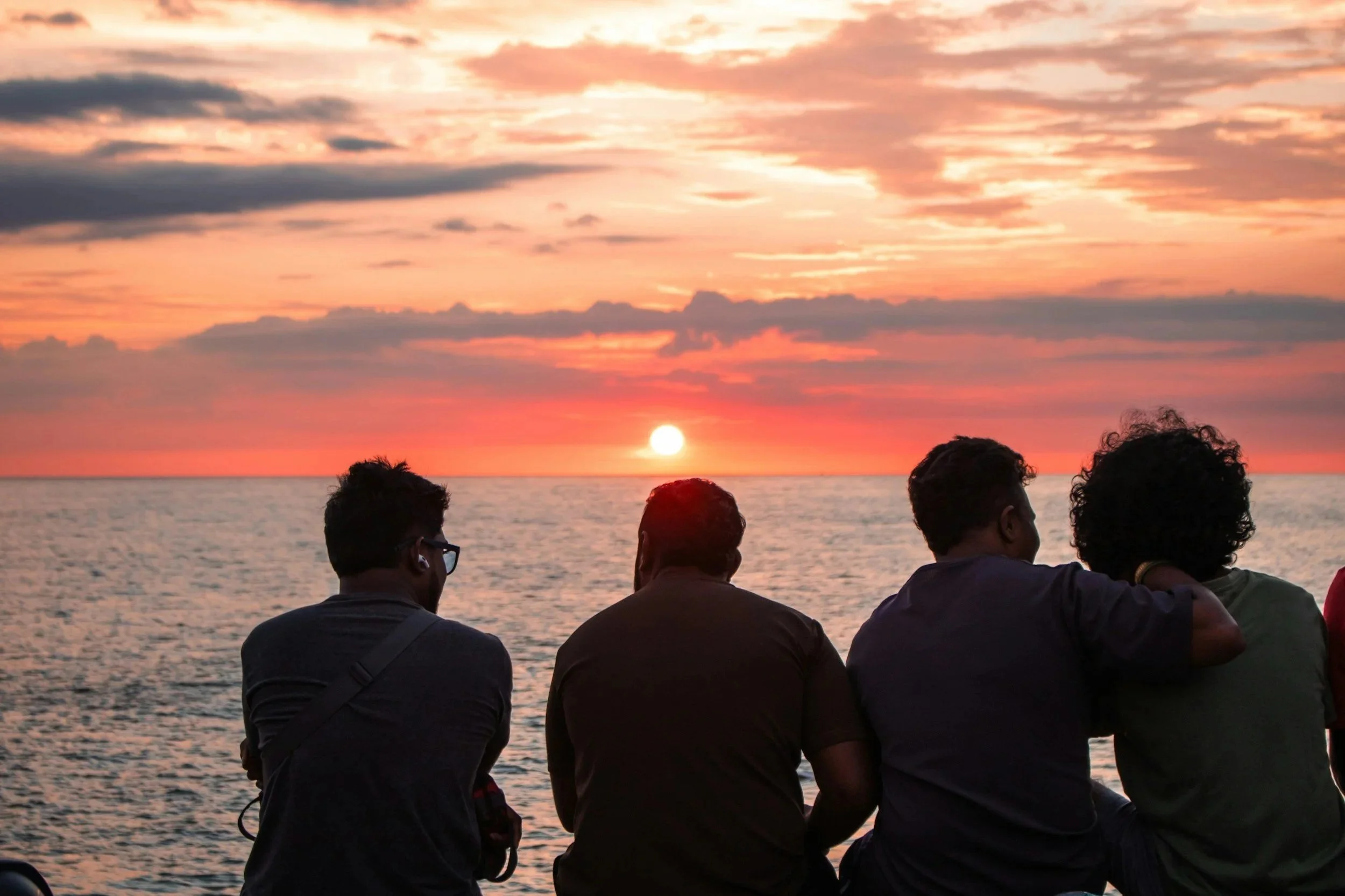 Sunset on beach, black figures of friends hanging out
