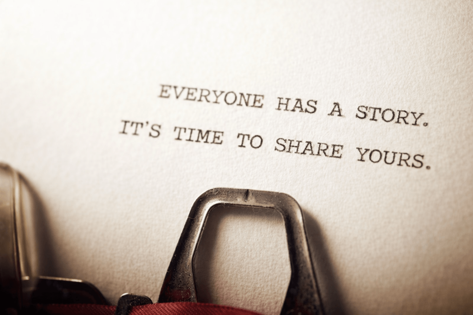 A close-up of a typewriter with a paper that reads, 'Everyone has a story. It's time to share yours.'