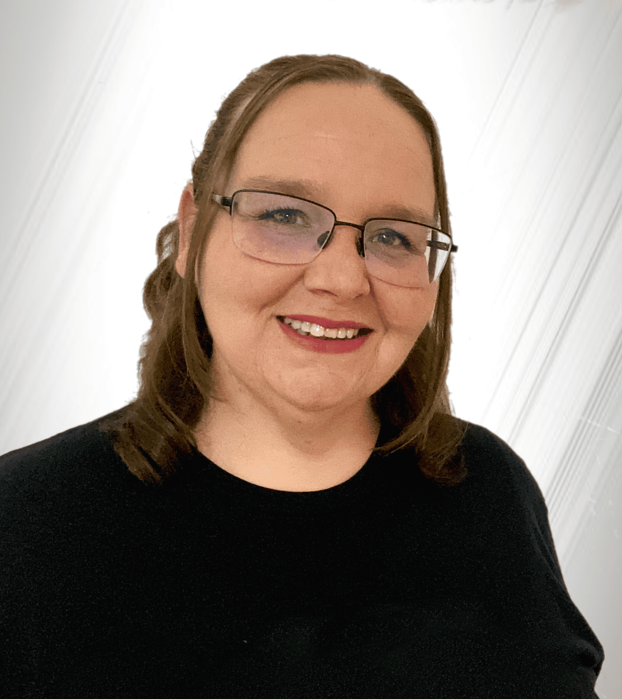Close-up of a woman with glasses, curly brown hair, wearing a black top, smiling against a plain off-white background.