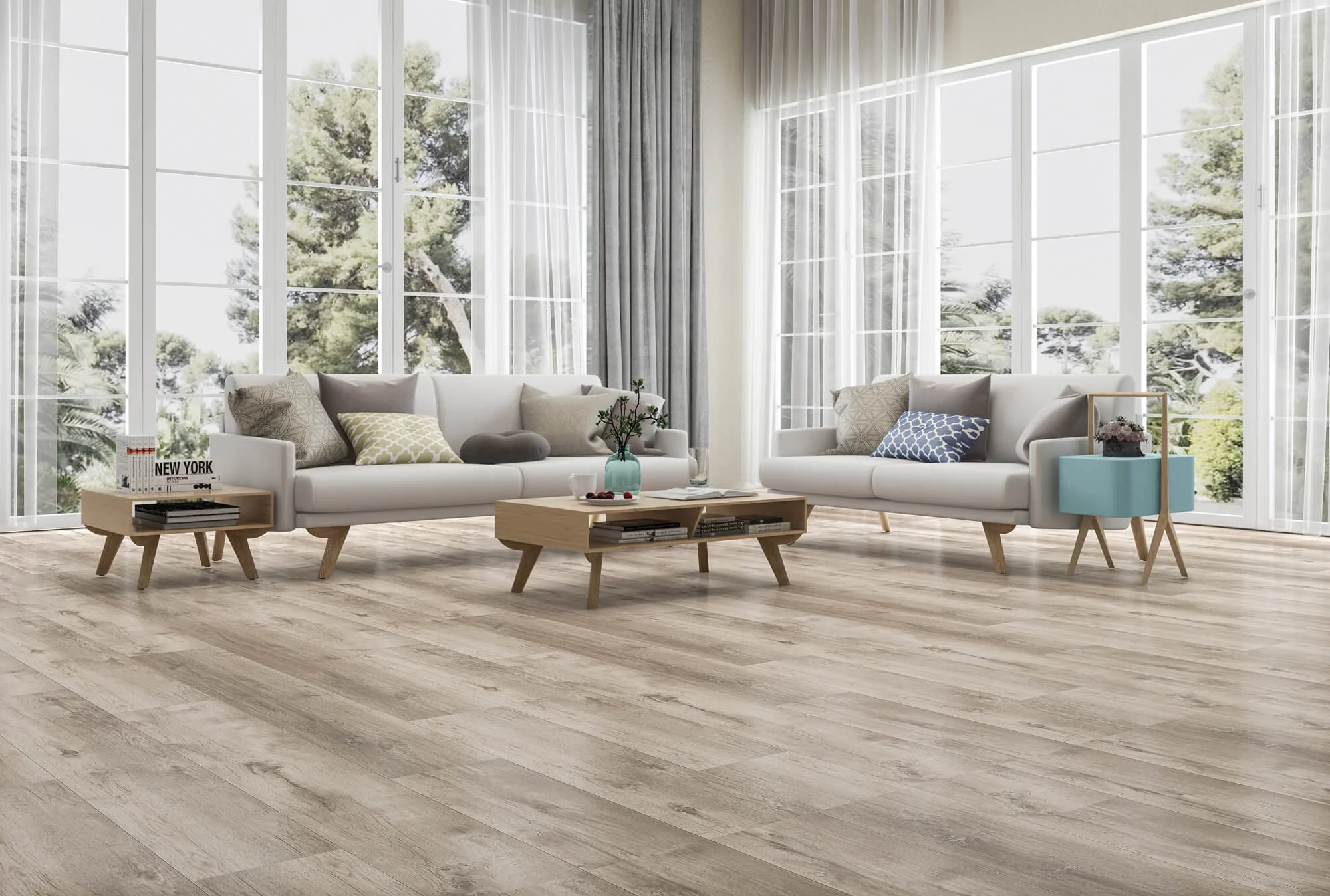 Bright living room with large windows, white sofas, a wooden coffee table, side table, and a blue accent table, all on light wood floors, with greenery outside.