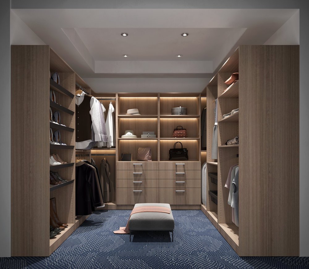 Walk-in closet with wooden shelves and drawers, clothing and accessories, and a cushioned bench in front, illuminated by recessed ceiling lights.