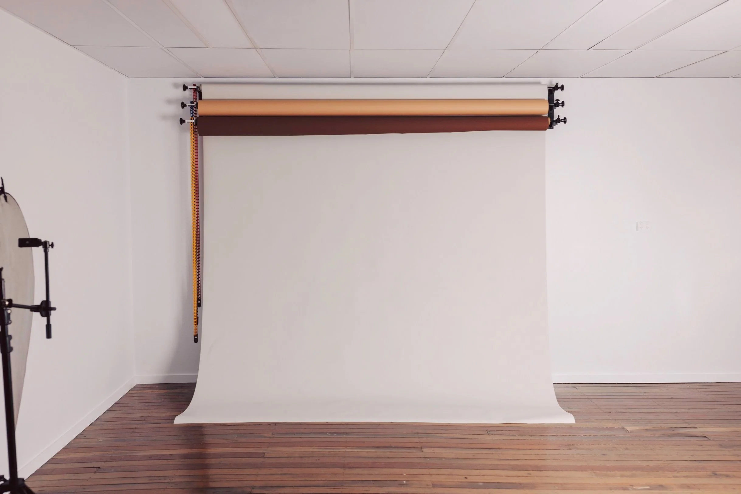 Photography studio with multiple backdrop rolls and a wooden floor.