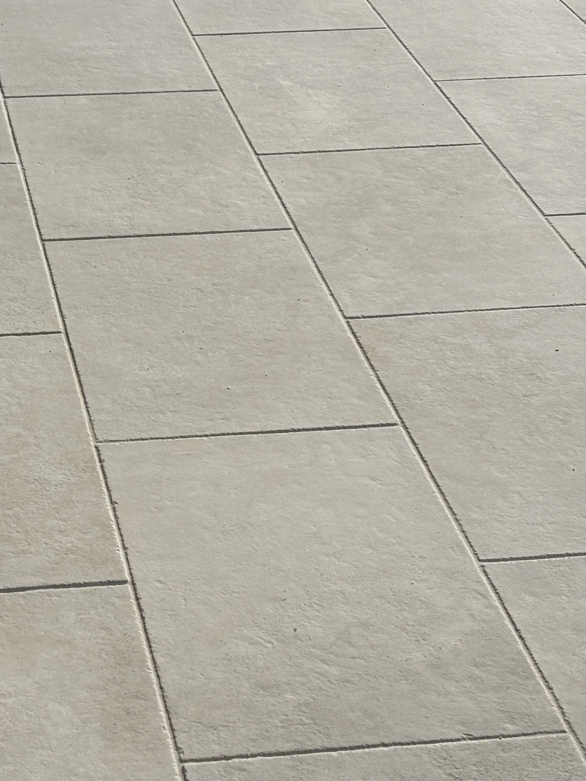 Close-up view of beige porcelain floor tiles with visible grout lines in Redcliffe.