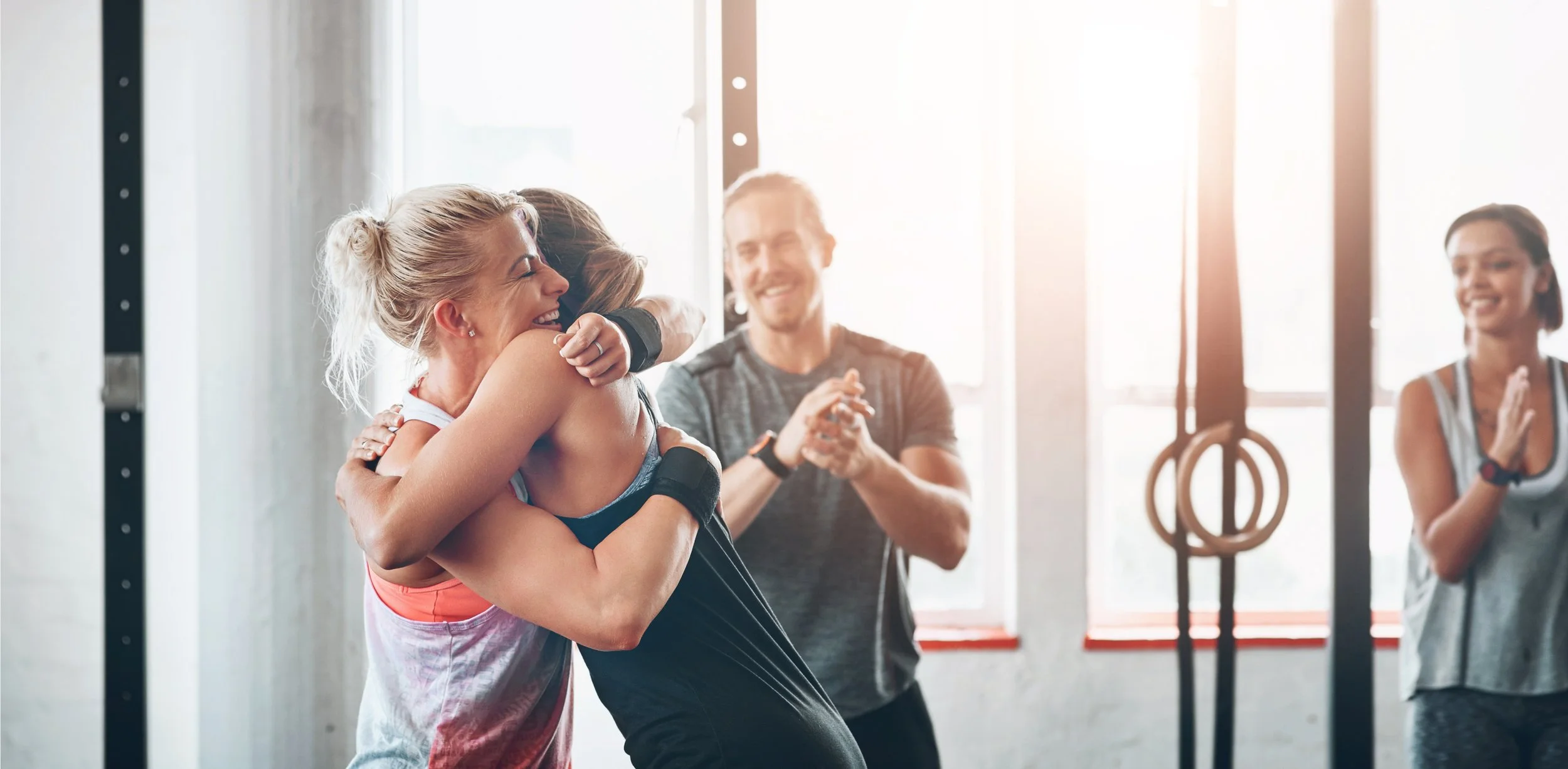 Two women hugging in ayoga-studio Soul Vibe Space in Limassol, with two other people clapping and smiling in the background.