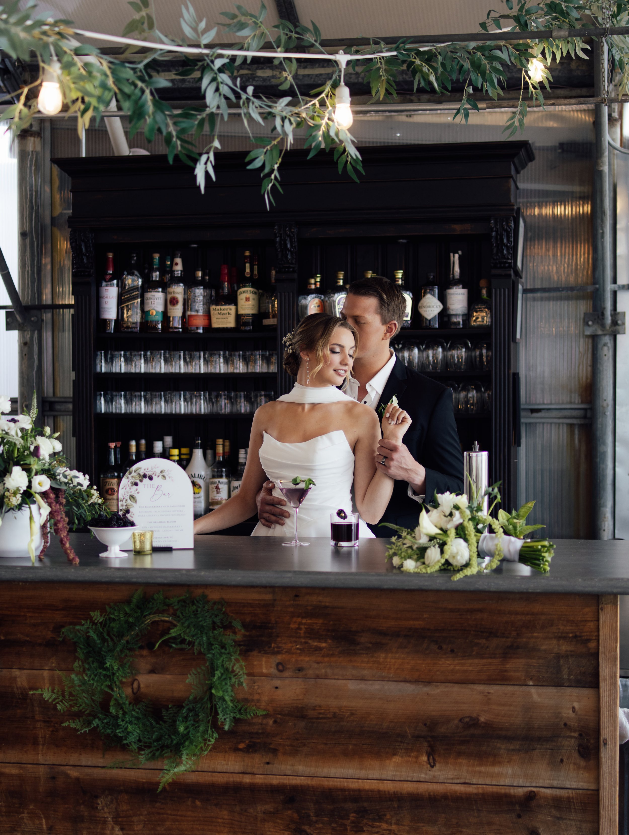 Married couple posing behind bar at The Greenhouse at Bittersweet