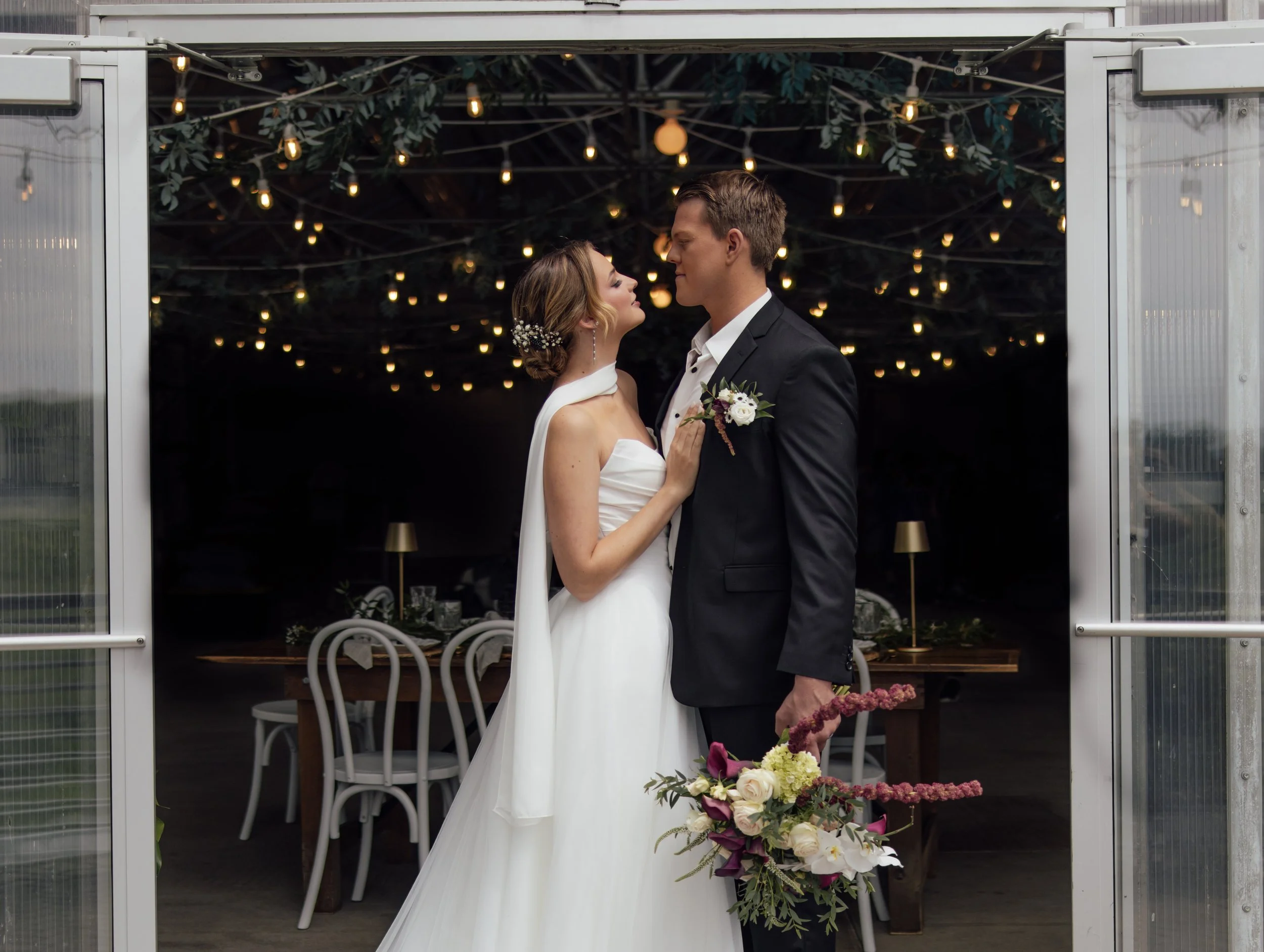 Newly married couple posing for portrait inside doors of The Greenhouse at Bittersweet