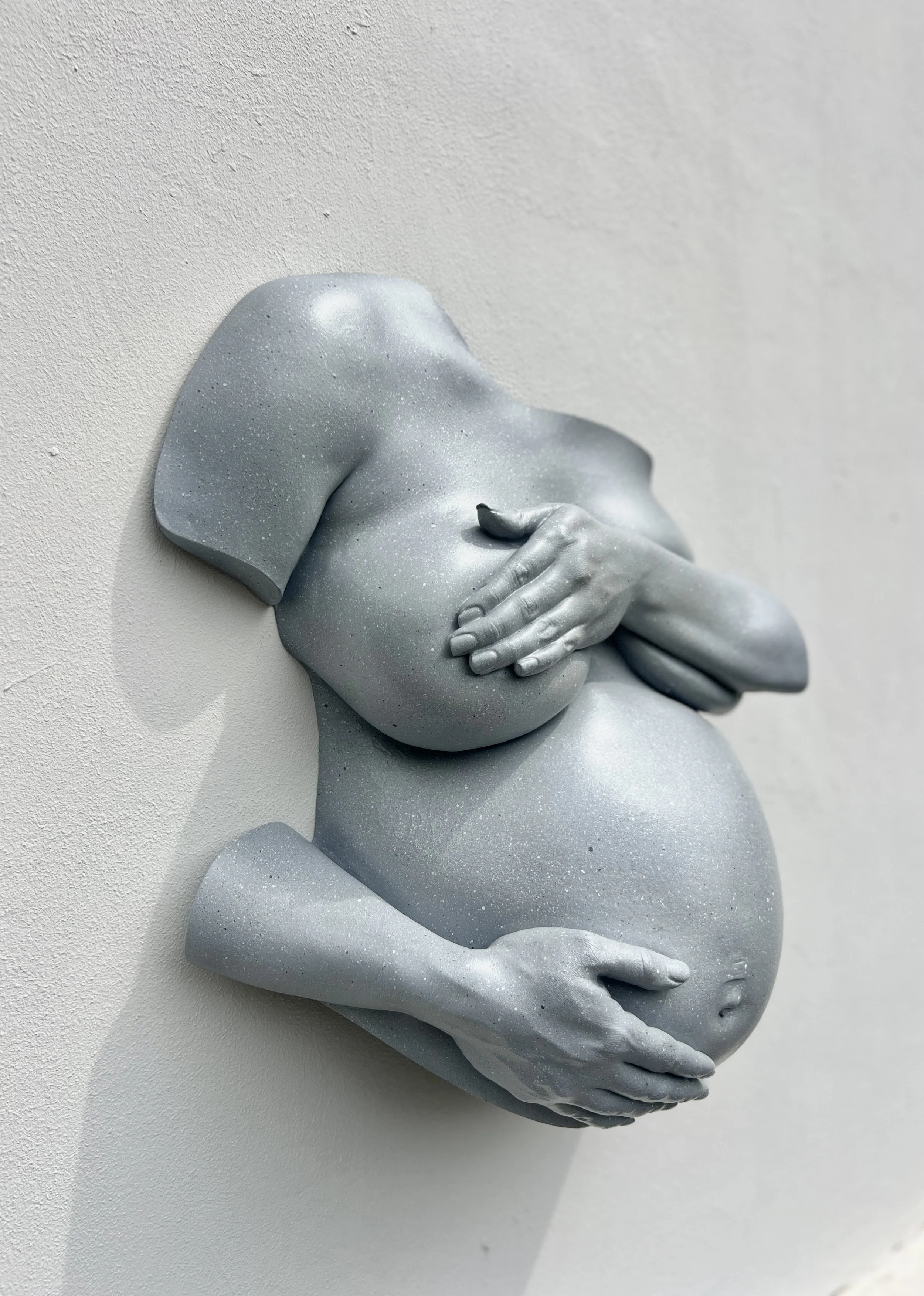 Lichtgrijs bodycasting beeld van zwangere vrouw in zijaanzicht met hand en onderarm over borsten en andere hand op buik, handgemaakt van hars met steeneffect afwerking, kunstwerk van Venus in Vorm.