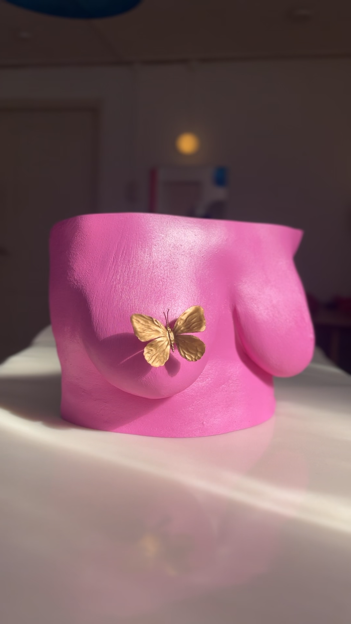 Roze body casting borstsculptuur met gouden vlinderornament op tepel, handgemaakt van hars met zijdeglans afwerking, kunstwerk van Venus in Vorm, gefotografeerd in het body casting atelier in zonlicht.