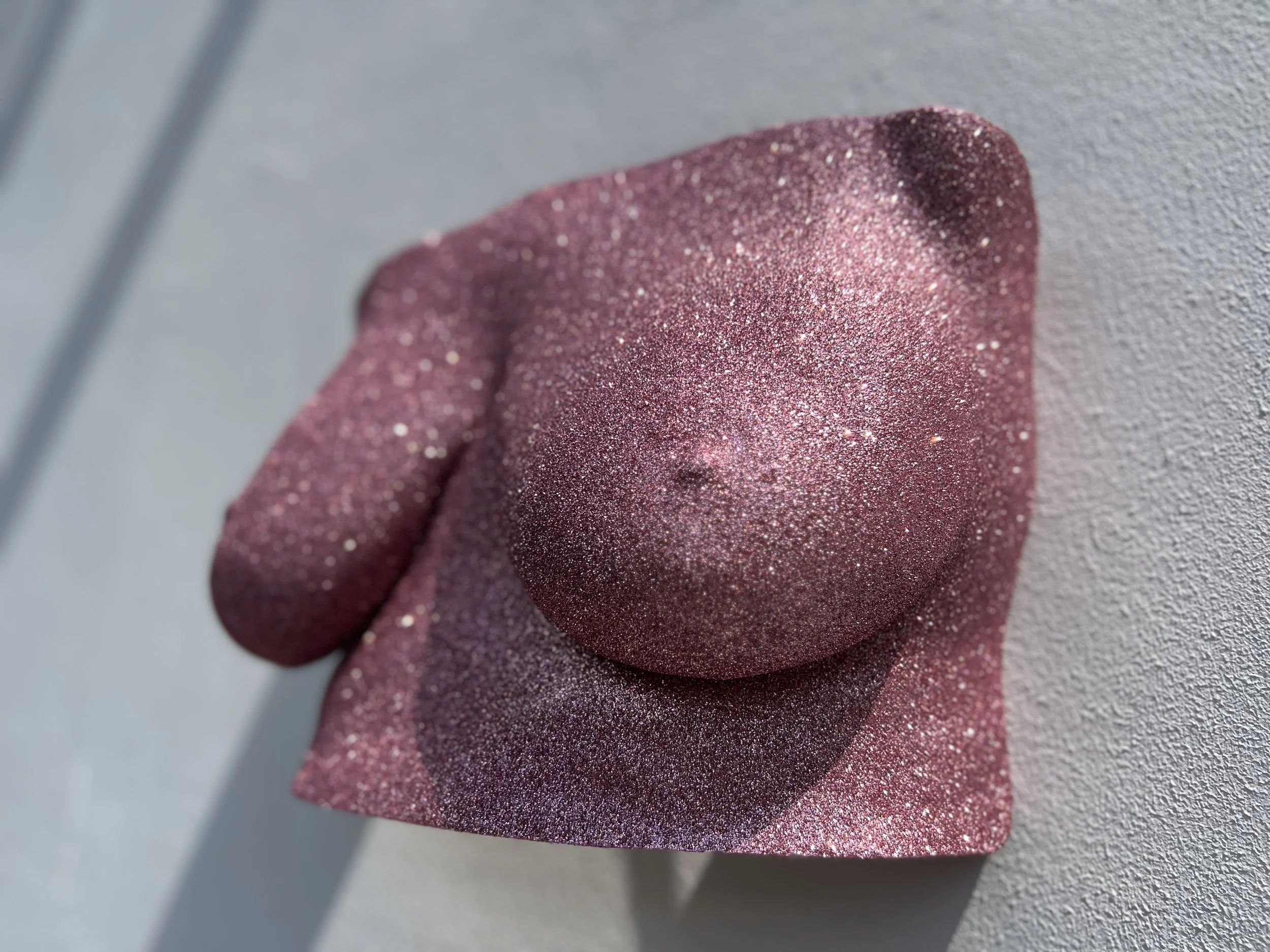 Bodycasting beeld van borstkas met rose gold glitters, handgemaakt van hars met glanzende afwerking, kunstwerk van Venus in Vorm, gefotografeerd buiten in zonlicht met schaduw onder de sculptuur.