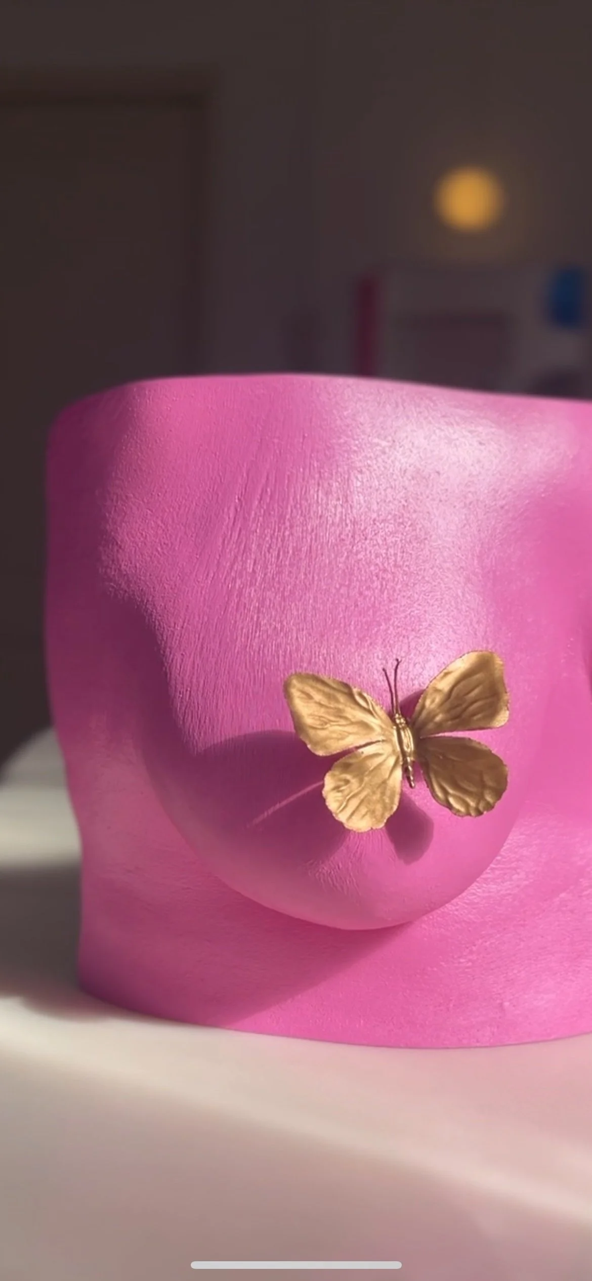 Detailfoto van roze bodycasting borstsculptuur met gouden vlinderornament op tepel, handgemaakt van hars met zijdeglans afwerking, kunstwerk van Venus in Vorm, gefotografeerd in het body casting atelier in zonlicht.